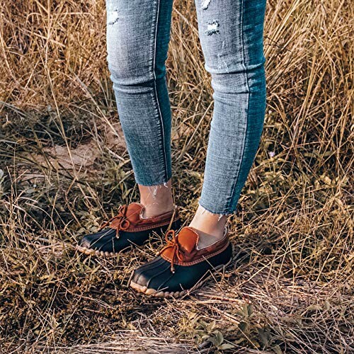 Person wearing duck boots and jeans in a grassy field.